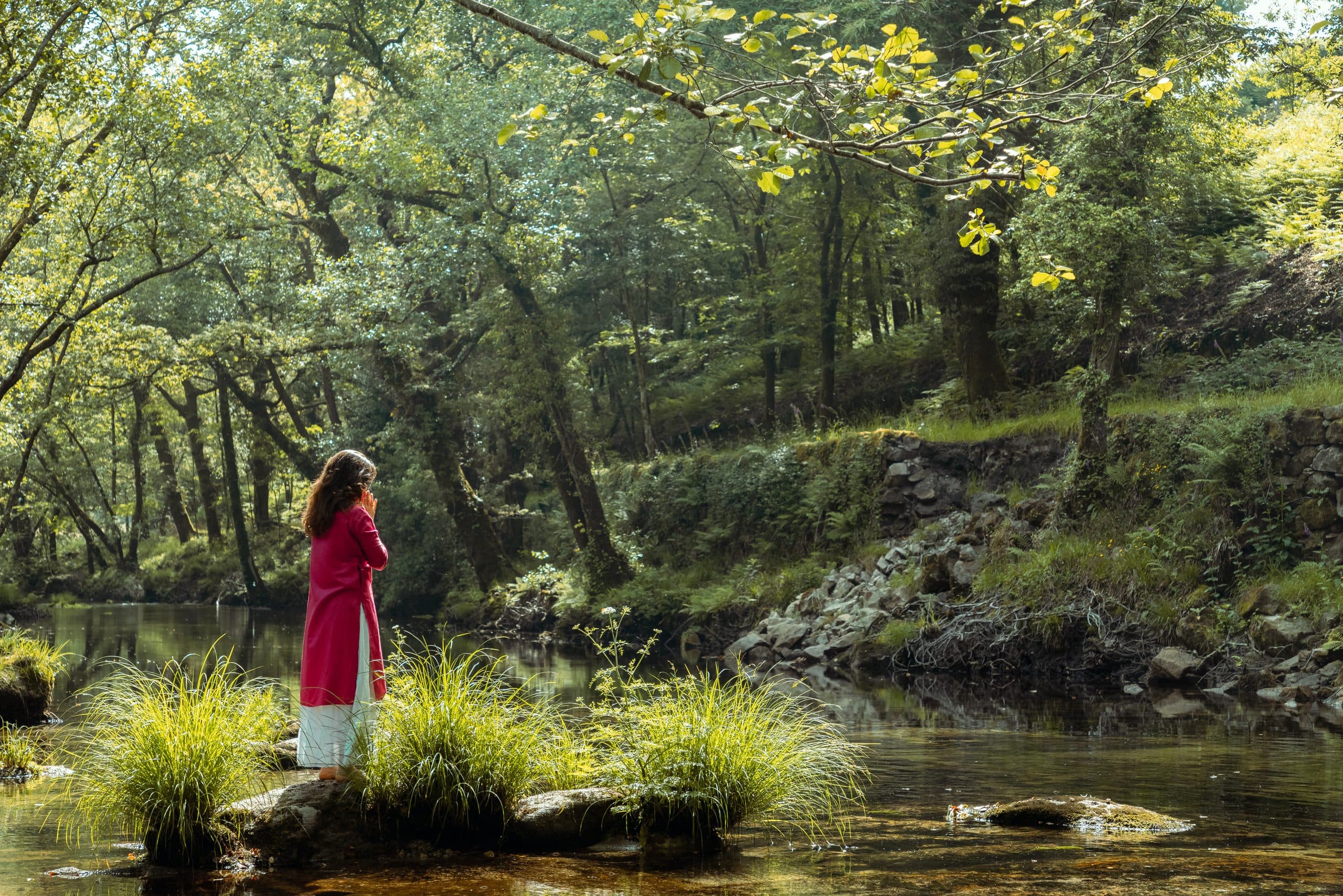 Alicia Corral de pie junto a un río en el bosque