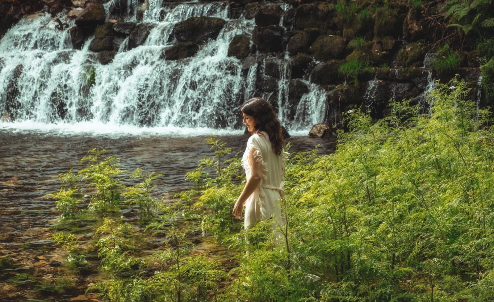 Alicia Corral junto a una cascada en la naturaleza